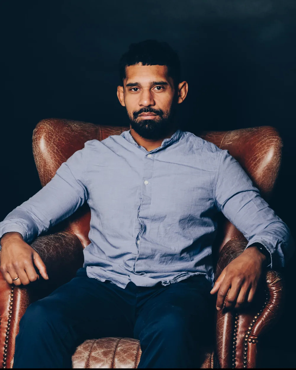 Rodrigo Fernandes, Jiu-Jitsu black belt and yoga teacher in Berlin, seated in a leather armchair